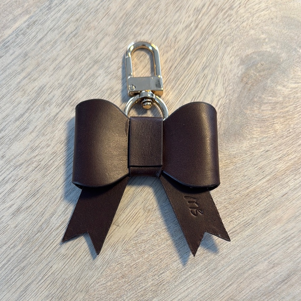 Elegant Brown Leather Bow Bag Charm with light gold hardware.